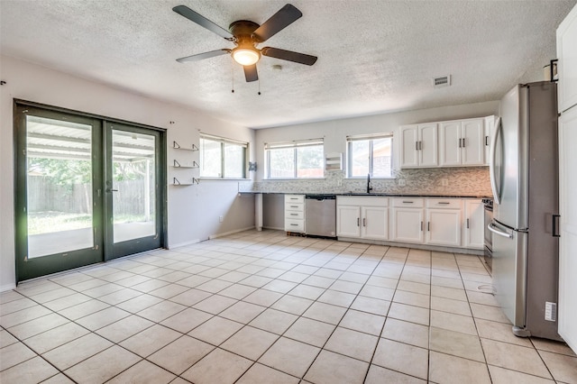 1709 Meadow Vly, Irving, TX 75060 - kitchen with stainless steel appliances, healthy amount of natural light, a textured ceiling, a ceiling fan, and white cabinetry