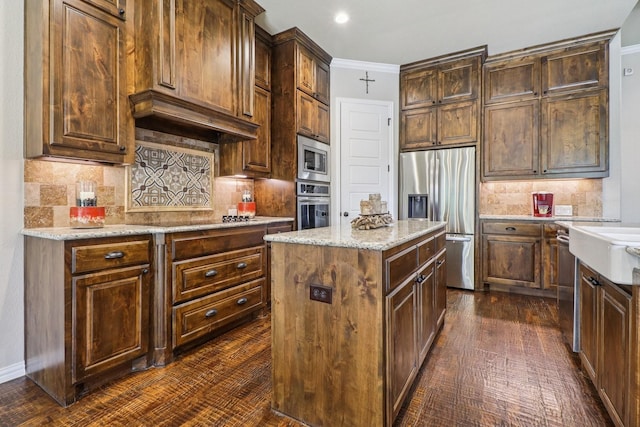 114 Piper Pkwy, Waxahachie, TX 75165 - kitchen with appliances with stainless steel finishes, decorative backsplash, a center island, light stone counters, and dark wood-style flooring