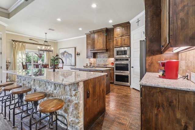 114 Piper Pkwy, Waxahachie, TX 75165 - kitchen with a sink, appliances with stainless steel finishes, a large island with sink, ornamental molding, and backsplash