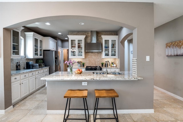 6312 Valley View Dr, Mckinney, TX 75071 - kitchen featuring wall chimney exhaust hood, a sink, stainless steel fridge with ice dispenser, backsplash, and a kitchen bar