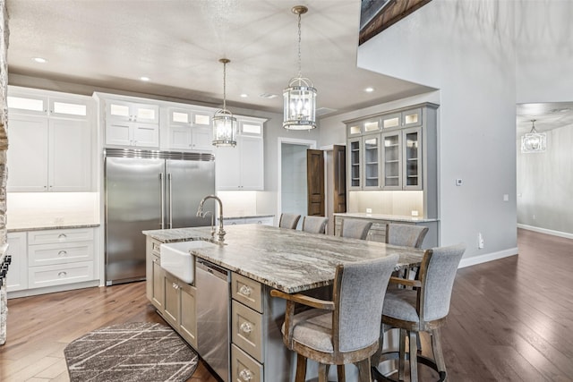 12877 Foutch Rd, Pilot Point, TX 76258 - kitchen with appliances with stainless steel finishes, a sink, hardwood / wood-style flooring, a chandelier, and a kitchen breakfast bar