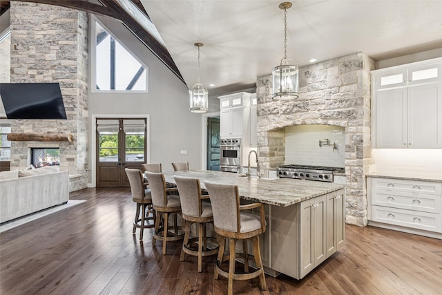 12877 Foutch Rd, Pilot Point, TX 76258 - kitchen featuring glass insert cabinets, white cabinetry, dark wood finished floors, a kitchen island with sink, and high vaulted ceiling