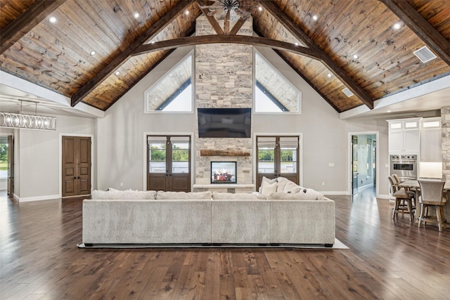 12877 Foutch Rd, Pilot Point, TX 76258 - living room with high vaulted ceiling, wooden ceiling with exposed beams, dark wood finished floors, a stone fireplace, and baseboards