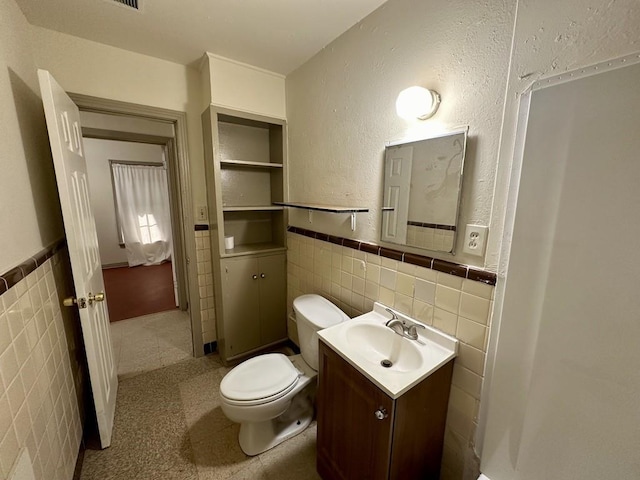 1517 Maple Dr, Garland, TX 75042 - bathroom featuring tile walls, wainscoting, vanity, and toilet
