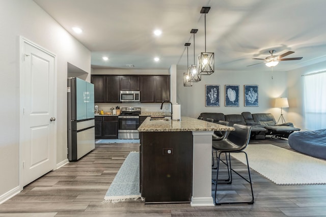 7020 Llano Dr, Waco, TX 76633 - kitchen with appliances with stainless steel finishes, open floor plan, dark brown cabinetry, wood finished floors, and recessed lighting