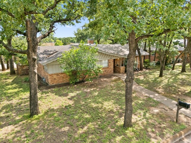 521 Brookview Dr, Hurst, TX 76054 - view of front of property featuring brick siding, a chimney, board and batten siding, and a front yard