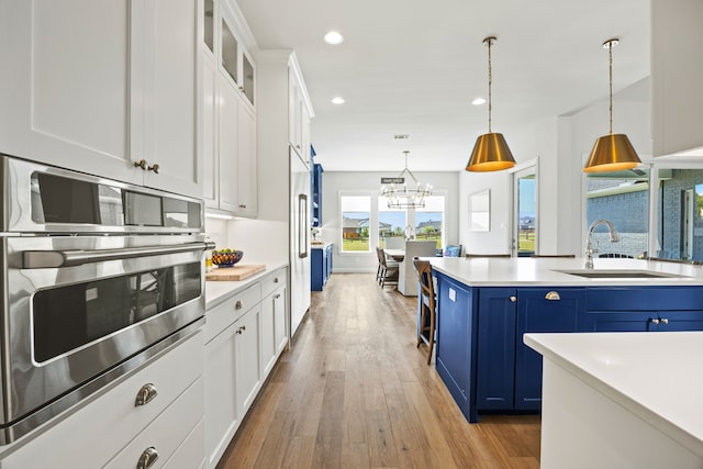 3201 Dovehill Dr, Northlake, TX 76247 - kitchen featuring blue cabinetry, a sink, recessed lighting, light wood finished floors, and light countertops