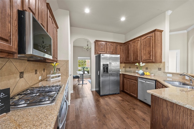 1825 Sanderlain Ln, Allen, TX 75002 - kitchen featuring stainless steel appliances, a sink, arched walkways, dark wood finished floors, and light stone counters