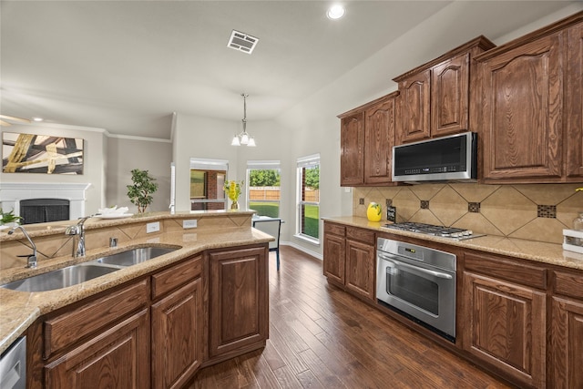 1825 Sanderlain Ln, Allen, TX 75002 - kitchen featuring stainless steel appliances, a sink, light stone counters, backsplash, and a fireplace