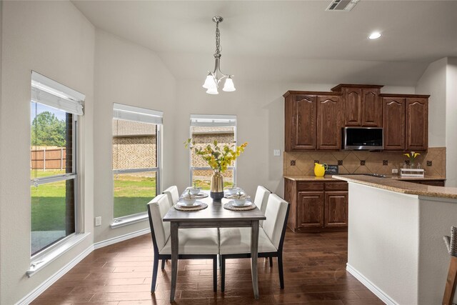 1825 Sanderlain Ln, Allen, TX 75002 - kitchen featuring stainless steel microwave, dark wood-style flooring, vaulted ceiling, backsplash, and a chandelier