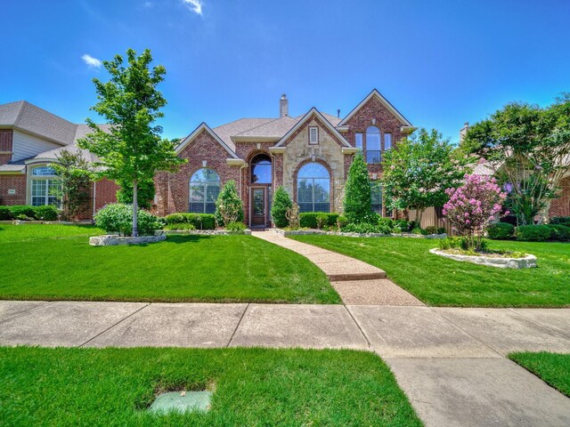 8009 Marathon Dr, Plano, TX 75024 - traditional-style house with a front lawn, brick siding, a chimney, and stone siding
