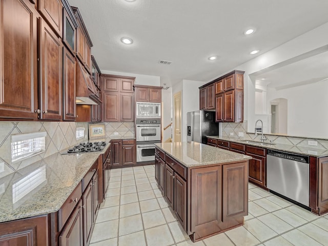 8009 Marathon Dr, Plano, TX 75024 - kitchen featuring stainless steel appliances, arched walkways, decorative backsplash, a center island, and light stone counters