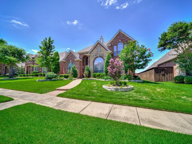 8009 Marathon Dr, Plano, TX 75024 - traditional-style house featuring a front lawn, a chimney, brick siding, and stone siding
