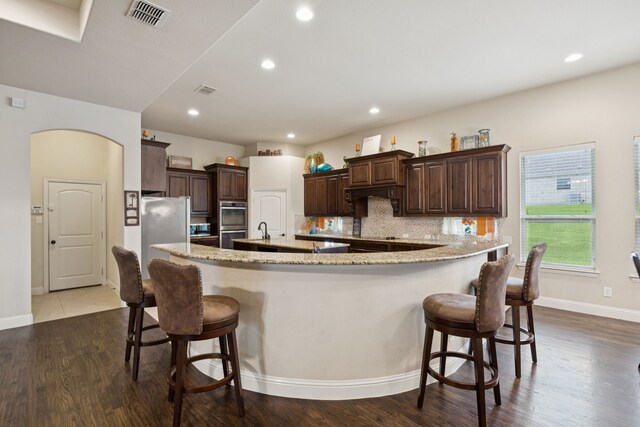 235 Bearclaw Cir, Aledo, TX 76008 - kitchen with stainless steel appliances, dark brown cabinetry, tasteful backsplash, a breakfast bar area, and a sink