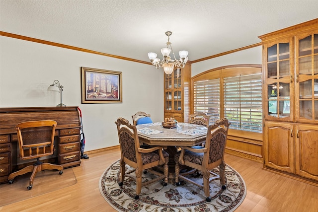 1419 Hinchliffe Rd, Mexia, TX 76667 - dining room with light wood-style flooring, a chandelier, crown molding, a textured ceiling, and baseboards