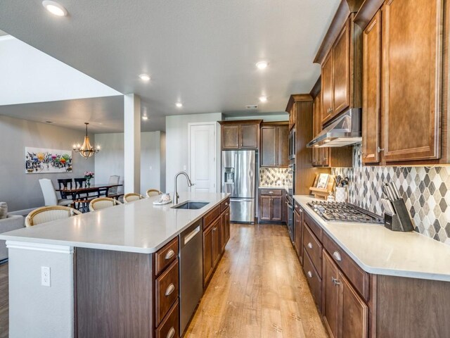 720 Lawndale St, Celina, TX 75009 - kitchen with stainless steel appliances, under cabinet range hood, a spacious island, baseboards, and backsplash