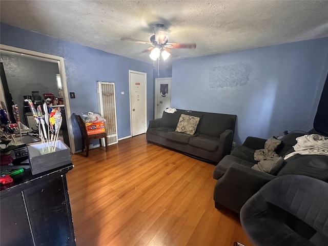 133 E Wanda Dr, Garland, TX 75040 - living room with a heating unit, a textured ceiling, ceiling fan, wood finished floors, and a textured wall