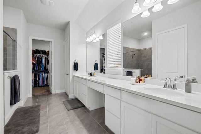 2705 Cumberland, The Colony, TX 75056 - bathroom featuring a tile shower, double vanity, tile patterned flooring, a walk in closet, and baseboards
