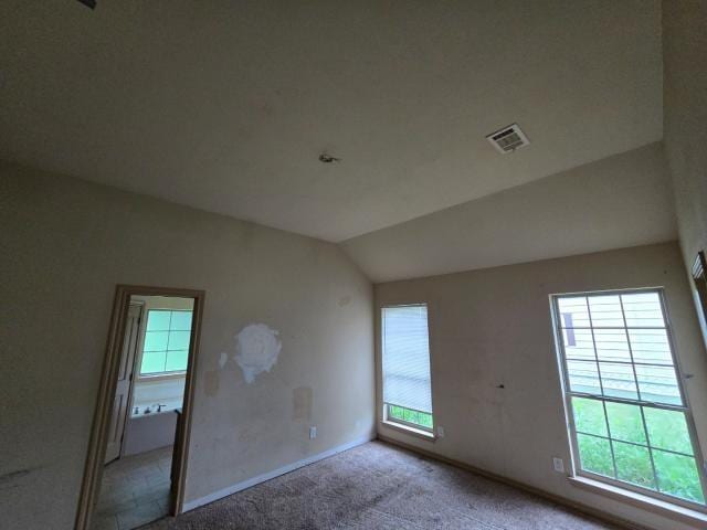carpeted empty room with vaulted ceiling and baseboards