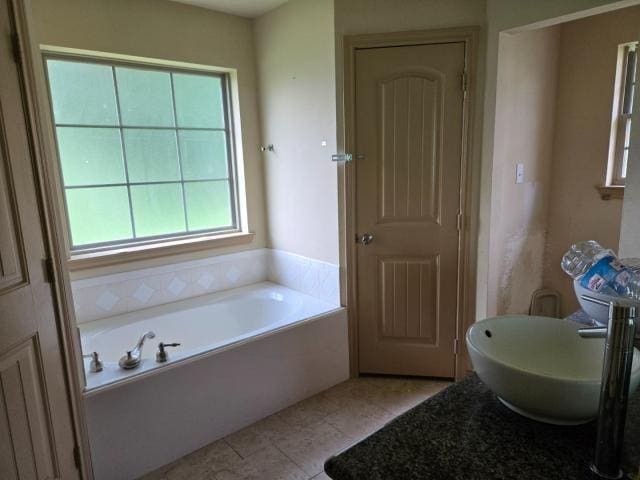bathroom featuring a garden tub, tile patterned floors, and a sink