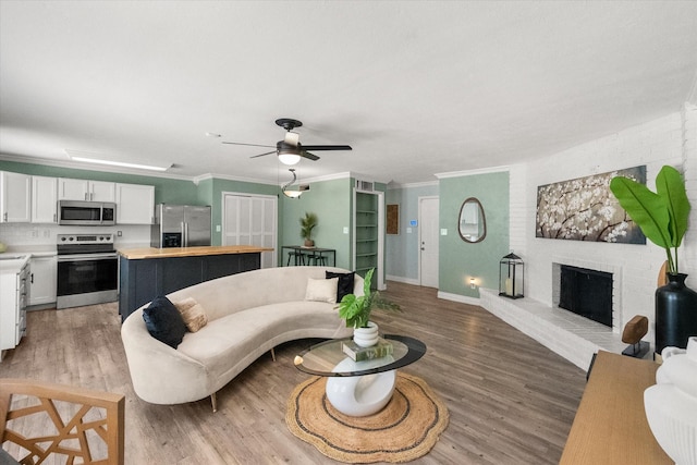 7817 Whirlwind Dr, Fort Worth, TX 76133 - living room featuring light wood-type flooring, a ceiling fan, a fireplace, and crown molding