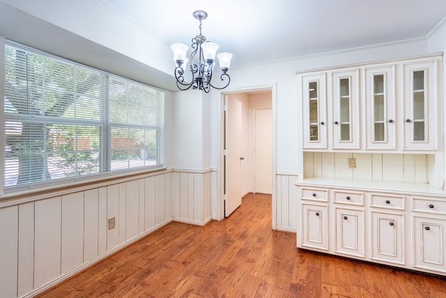110 Sunview St, Sunnyvale, TX 75182 - unfurnished dining area with a chandelier, light wood-type flooring, plenty of natural light, a wainscoted wall, and ornamental molding