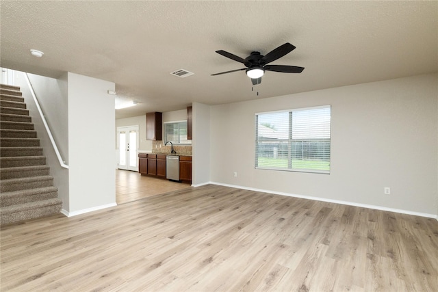 2133 Bliss Rd, Fort Worth, TX 76177 - unfurnished living room featuring light wood-style floors, stairway, baseboards, ceiling fan, and a textured ceiling