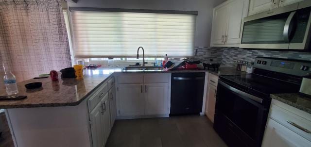 918 Greenbriar Dr, Garland, TX 75043 - kitchen with stainless steel microwave, black range with electric stovetop, dishwashing machine, a sink, and white cabinetry