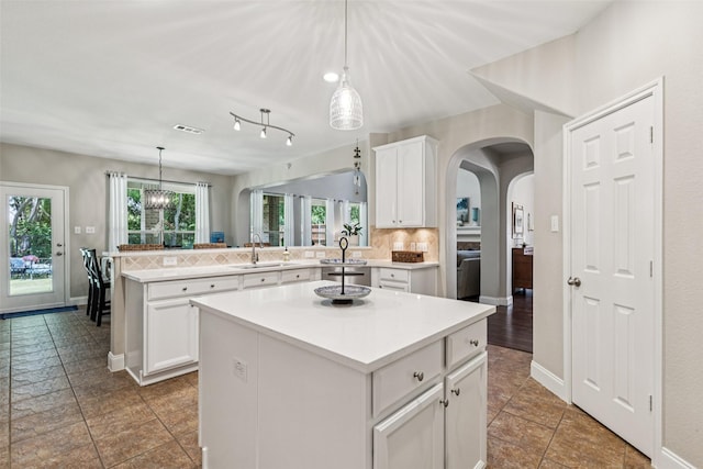 11310 Seguin Dr, Frisco, TX 75035 - kitchen featuring a sink, a center island, backsplash, arched walkways, and a peninsula