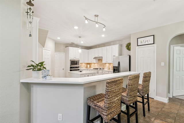 11310 Seguin Dr, Frisco, TX 75035 - kitchen with stainless steel appliances, decorative backsplash, a kitchen bar, light countertops, and under cabinet range hood
