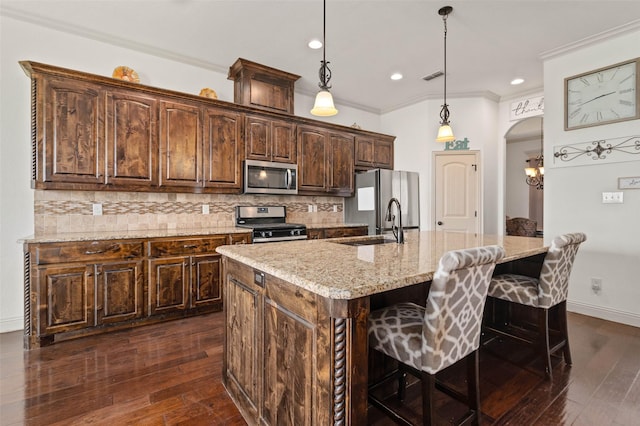 705 La Paloma Rd, Sanger, TX 76266 - kitchen with stainless steel appliances, ornamental molding, backsplash, dark brown cabinets, and a center island with sink