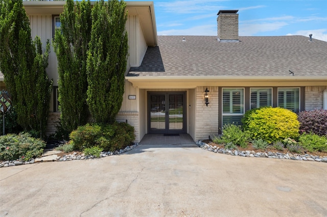 6015 Meadowcreek Dr, Dallas, TX 75248 - view of exterior entry with french doors, a shingled roof, a chimney, and brick siding