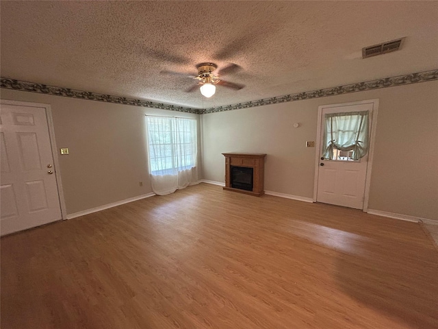 7834 Womack Rd, Shreveport, LA 71107 - unfurnished living room with ceiling fan, wood finished floors, a glass covered fireplace, a textured ceiling, and baseboards
