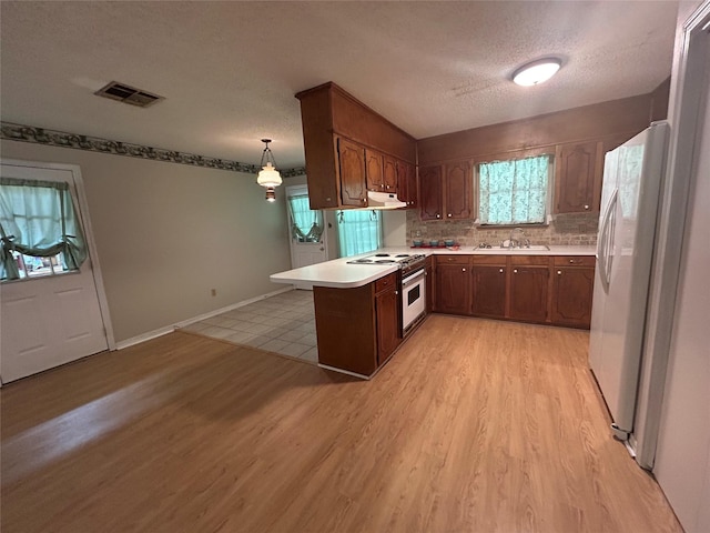 7834 Womack Rd, Shreveport, LA 71107 - kitchen with white appliances, a peninsula, light countertops, a sink, and under cabinet range hood