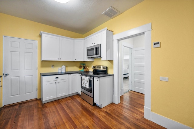 308 W Heard St, Cleburne, TX 76033 - kitchen with appliances with stainless steel finishes, white cabinetry, dark wood finished floors, and dark countertops