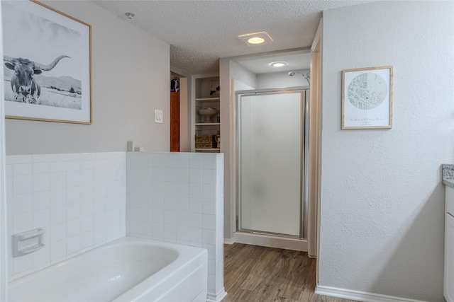 2101 Park Willow Ln Unit A, Arlington, TX 76011 - full bathroom with a textured ceiling, wood finished floors, a bath, a stall shower, and baseboards