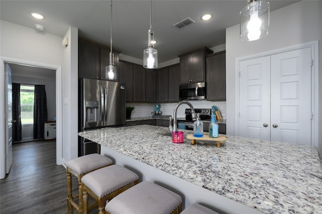 110 Thode St, Whitesboro, TX 76273 - kitchen featuring stainless steel appliances, light stone countertops, backsplash, dark wood finished floors, and a breakfast bar area