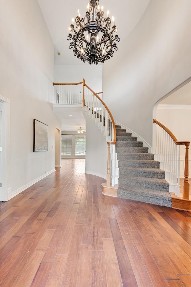 402 Thistle Ct, Southlake, TX 76092 - stairway featuring wood-type flooring, a towering ceiling, a chandelier, arched walkways, and baseboards