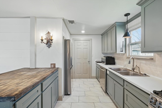 932 N Woods St, Sherman, TX 75092 - kitchen with stainless steel appliances, a sink, gray cabinetry, tasteful backsplash, and butcher block countertops