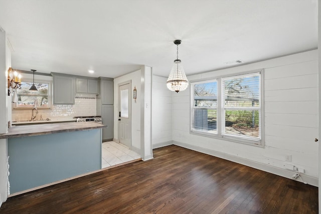 932 N Woods St, Sherman, TX 75092 - kitchen featuring gray cabinets, a chandelier, healthy amount of natural light, wood finished floors, and wood walls