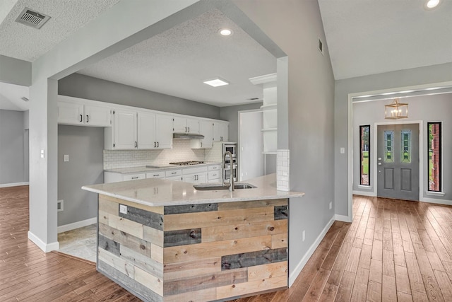 2310 N Walnut Grove Rd, Midlothian, TX 76065 - kitchen with a sink, light wood-type flooring, white cabinetry, stainless steel gas stovetop, and a textured ceiling