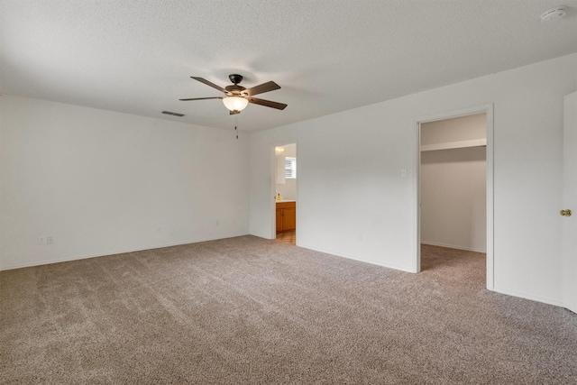 2310 N Walnut Grove Rd, Midlothian, TX 76065 - unfurnished bedroom featuring a walk in closet, light carpet, a textured ceiling, ceiling fan, and connected bathroom