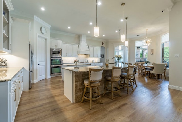 3340 Pleasantville Rd, Midlothian, TX 76065 - kitchen with stainless steel appliances, premium range hood, a large island with sink, light wood-type flooring, and decorative backsplash