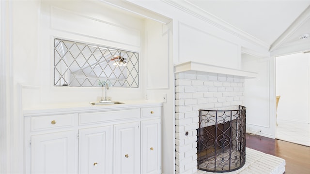 411 Roaring Springs Dr, Allen, TX 75002 - detailed view of wood finished floors, crown molding, bar with sink, and a brick fireplace