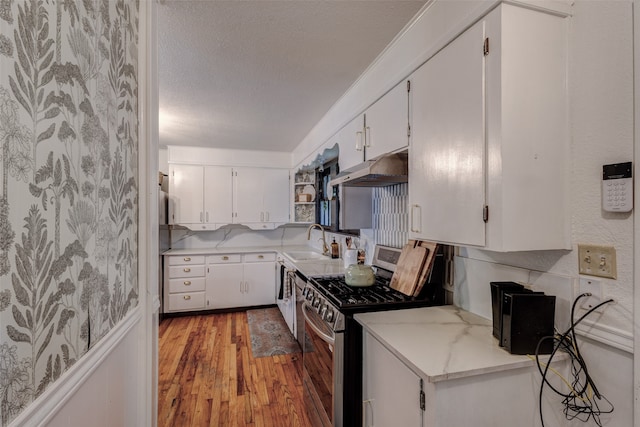 440 S Main St, Springtown, TX 76082 - kitchen featuring stainless steel gas stove, under cabinet range hood, light wood-style floors, white cabinetry, and a textured ceiling