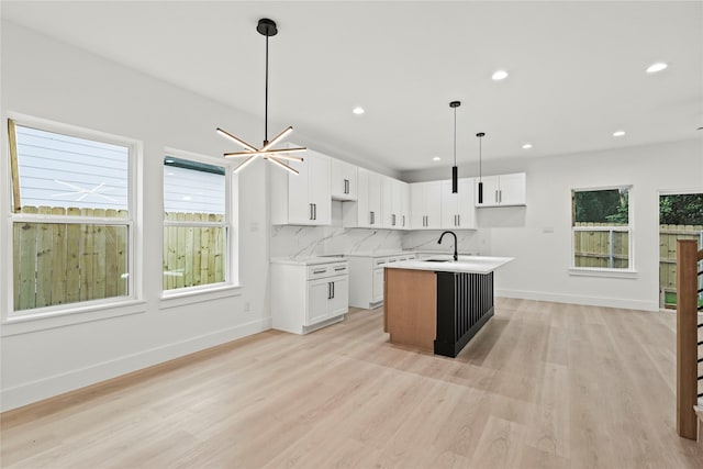 4523 Wahoo St, Dallas, TX 75210 - kitchen featuring light wood-type flooring, a kitchen island with sink, recessed lighting, backsplash, and hanging light fixtures