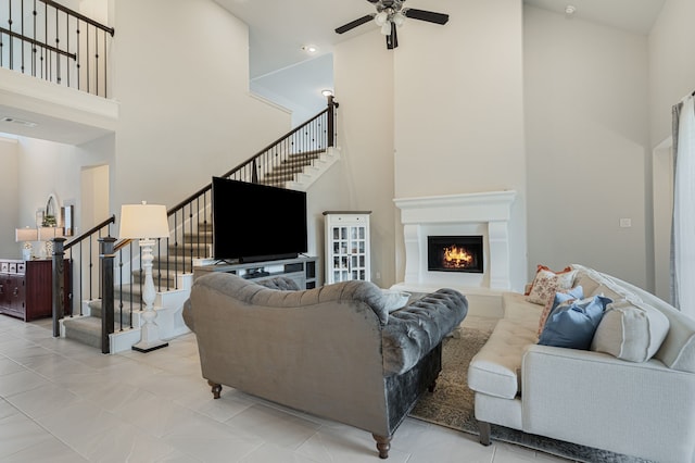 7020 Cross Point Ln, Little Elm, TX 76227 - living room featuring a towering ceiling, stairs, ceiling fan, and a warm lit fireplace