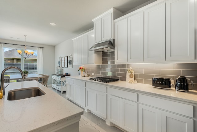 7020 Cross Point Ln, Little Elm, TX 76227 - kitchen featuring under cabinet range hood, a sink, a chandelier, stainless steel gas cooktop, and white cabinets