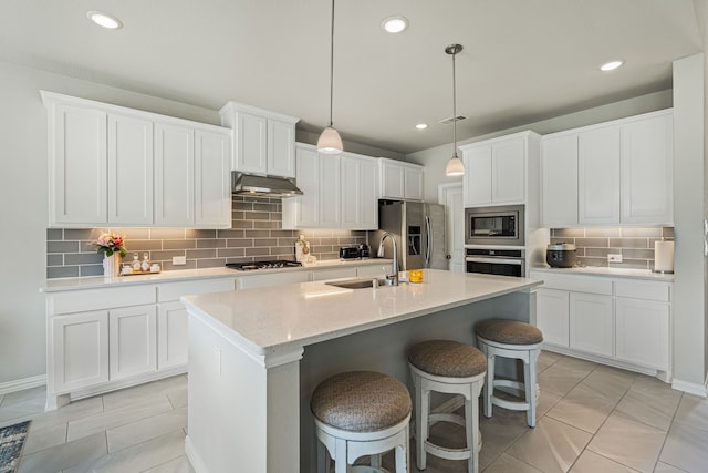 7020 Cross Point Ln, Little Elm, TX 76227 - kitchen with appliances with stainless steel finishes, under cabinet range hood, a sink, tasteful backsplash, and an island with sink