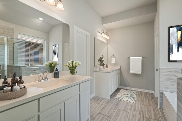 7020 Cross Point Ln, Little Elm, TX 76227 - bathroom with two vanities, a stall shower, baseboards, a tub to relax in, and lofted ceiling